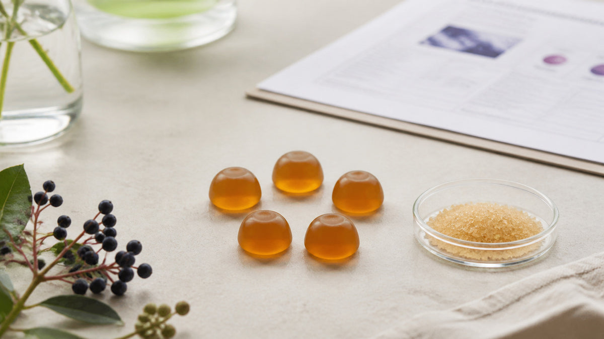 Five unbranded amber gummies beside a neutral ingredient sheet on an editorial desk